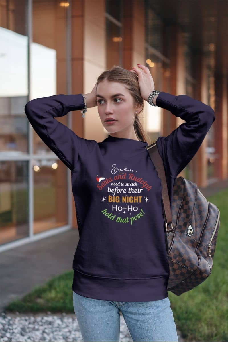 holiday humor pullover displaying a girl wearing a purple sweatshirt with text 'Event Santa & Rudolph Need to Stretch Before their Big Night. Ho-Ho-Hold That Pose!'