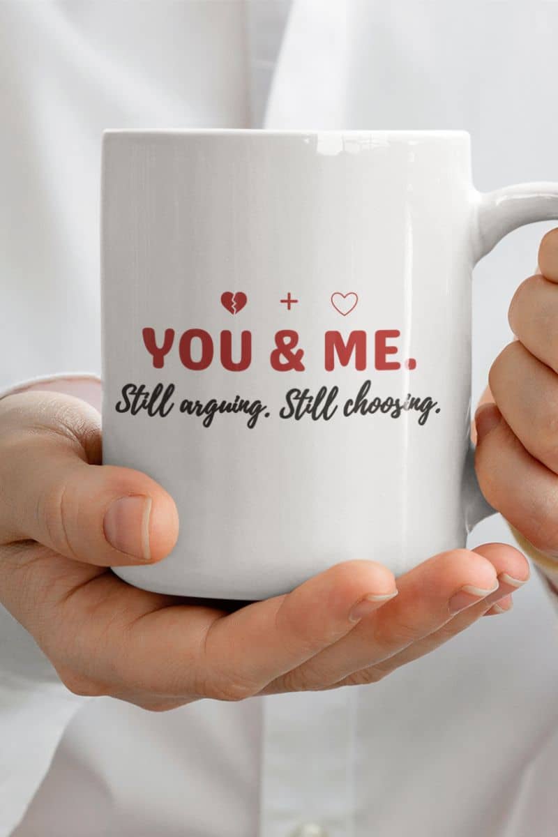 honest love quote mug with a white mug held by hands with text 'YOU & ME. Still arguing, Still choosing.'
