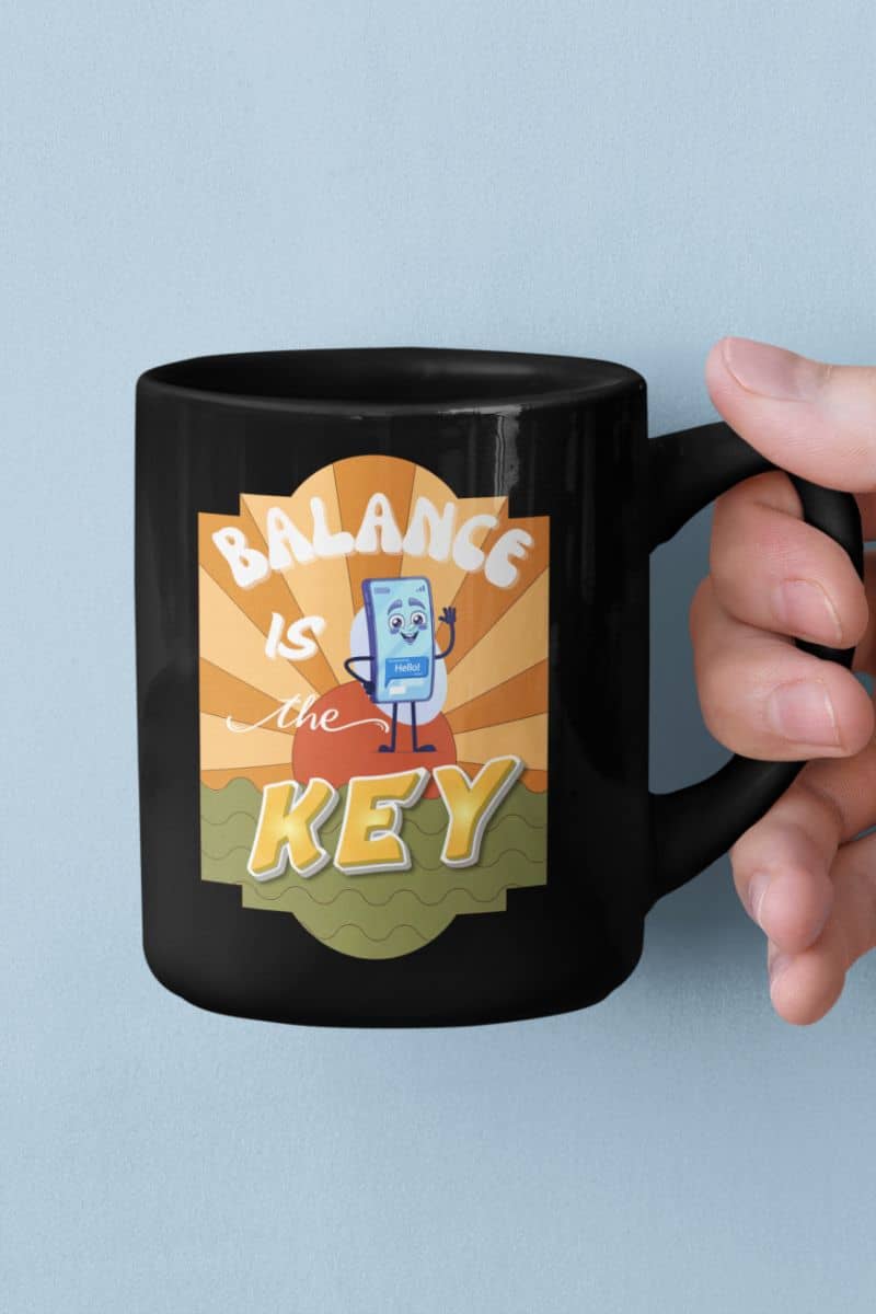 inspirational gift mug with a black mug with 'Balance is the Key' design held by a hand against a light blue background