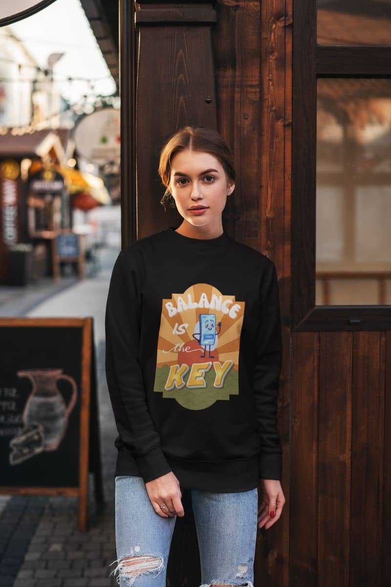 inspirational quote sweatshirt with a person wearing a black sweatshirt with a colorful graphic design, standing in front of a wooden door.