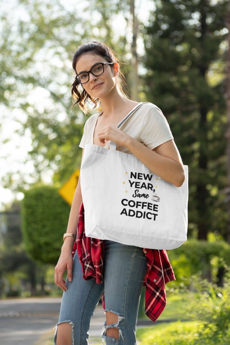 inspirational quote tote with a woman carying a tote bag with text 'New Year, Same Coffee Addict' outdoors