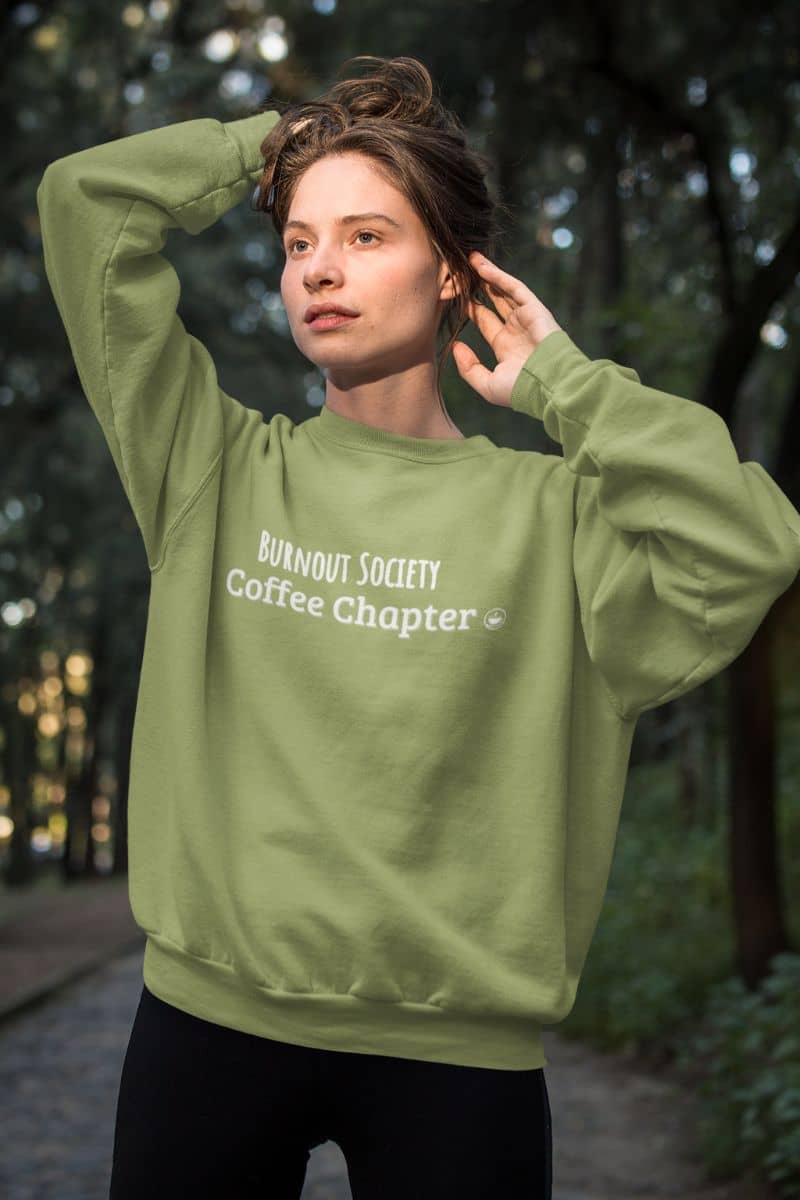 introvert burnout gear with a person wearing a green sweatshirt with text in a forest setting