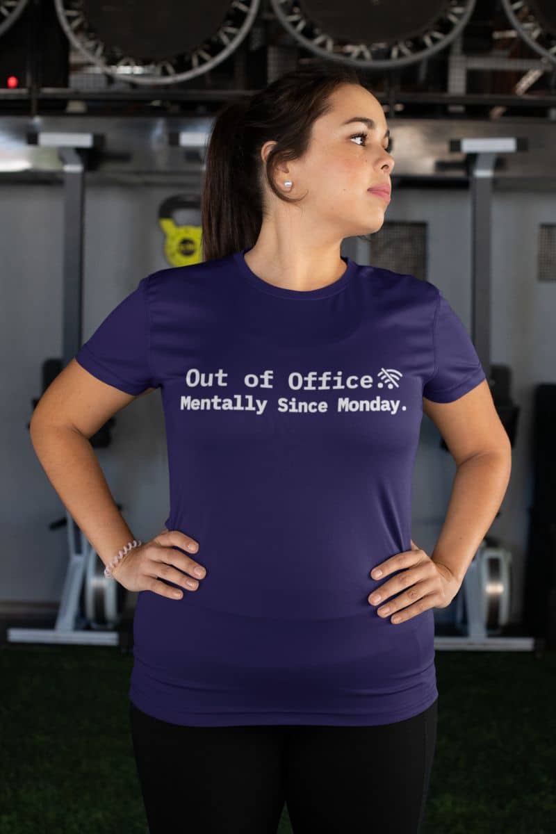 introvert coworker tee with a woman wearing a purple t-shirt with text 'Out of Office. Mentally Since Monday.' in an indoor setting