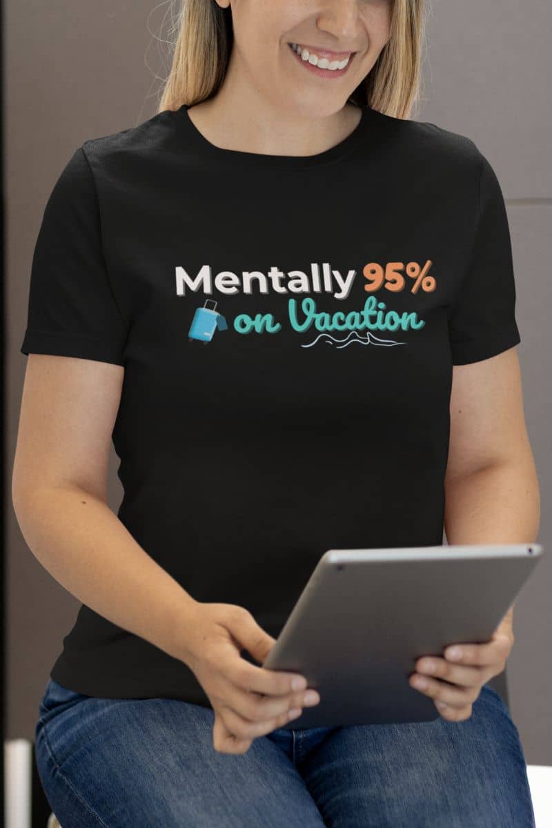 introvert vacation shirt with a person wearing a black t-shirt with humorous text 'Mentally 95% on Vacation' and holding a tablet.