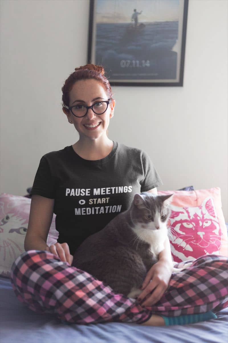 meditation humor shirt featuring a woman wearing a t-shirt with text 'Pause Meetings, Start Meditation', hugging a cat