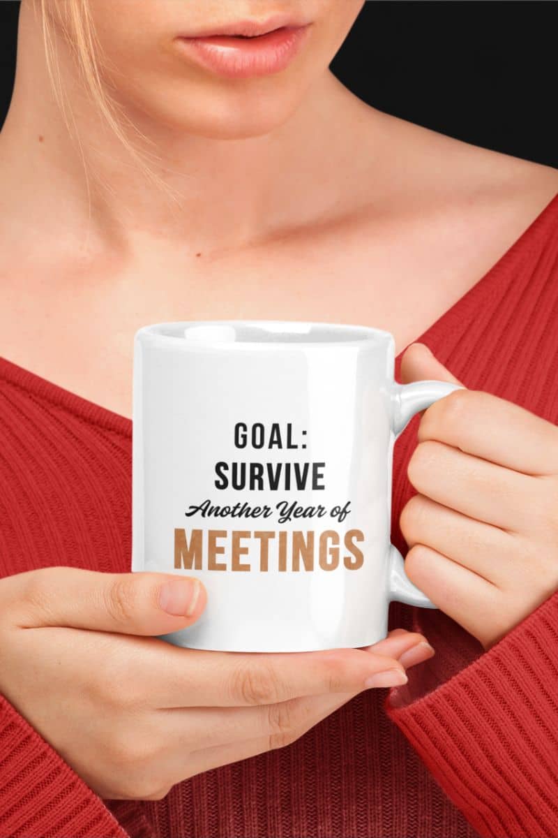 meeting humor mug with a person holding a white mug with text 'Goal: Survive Another Year of Meetings' against a black background