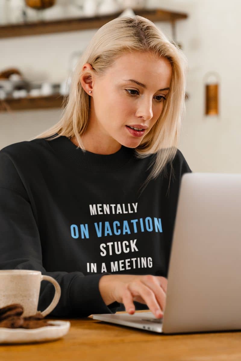 meeting humor sweatshirt featuring a woman wearing a black sweatshirt with humorous text, using a laptop in a home setting.