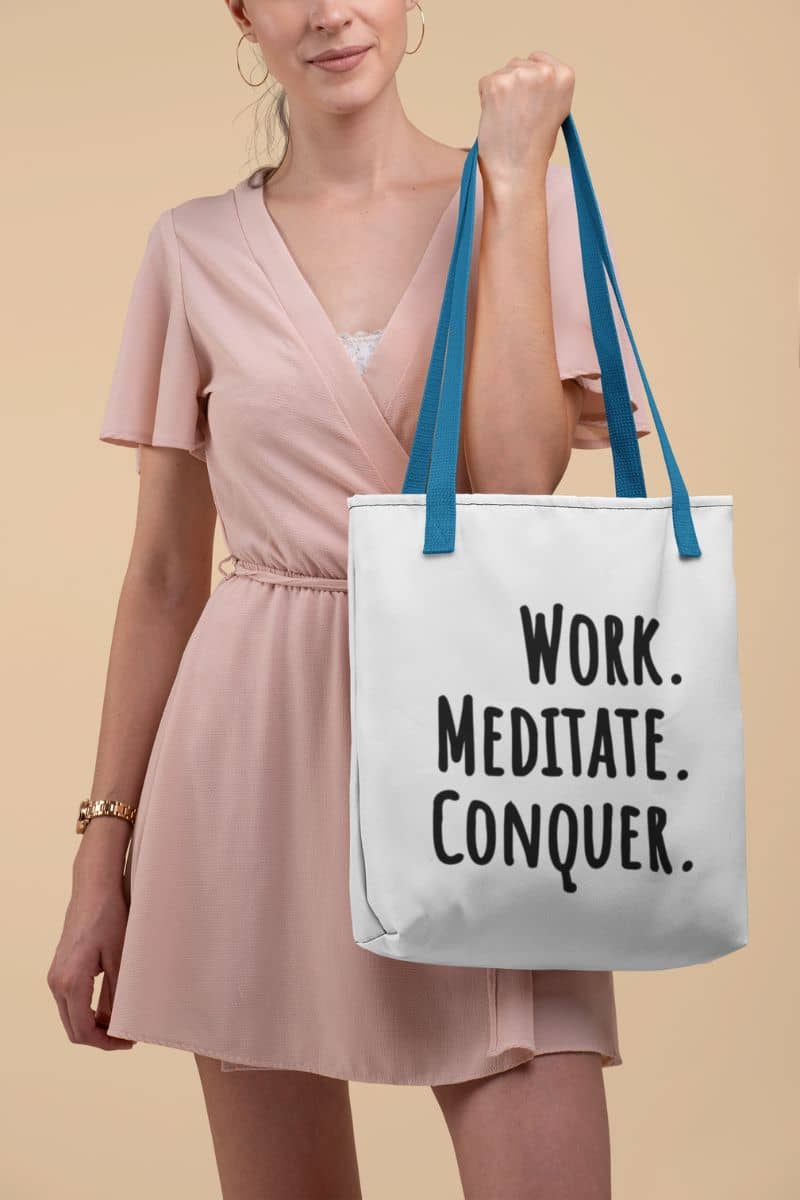 mindfulness tote bag with a woman holding a tote bag with 'Work. Meditate. Conquer.' text on a beige background