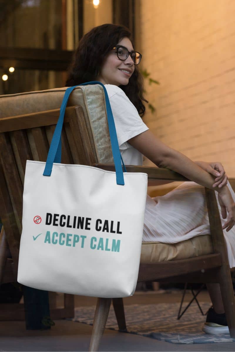 mindfulness tote bag with a woman sitting on a bench with a tote bag that says 'Decline Call Accept Calm'.