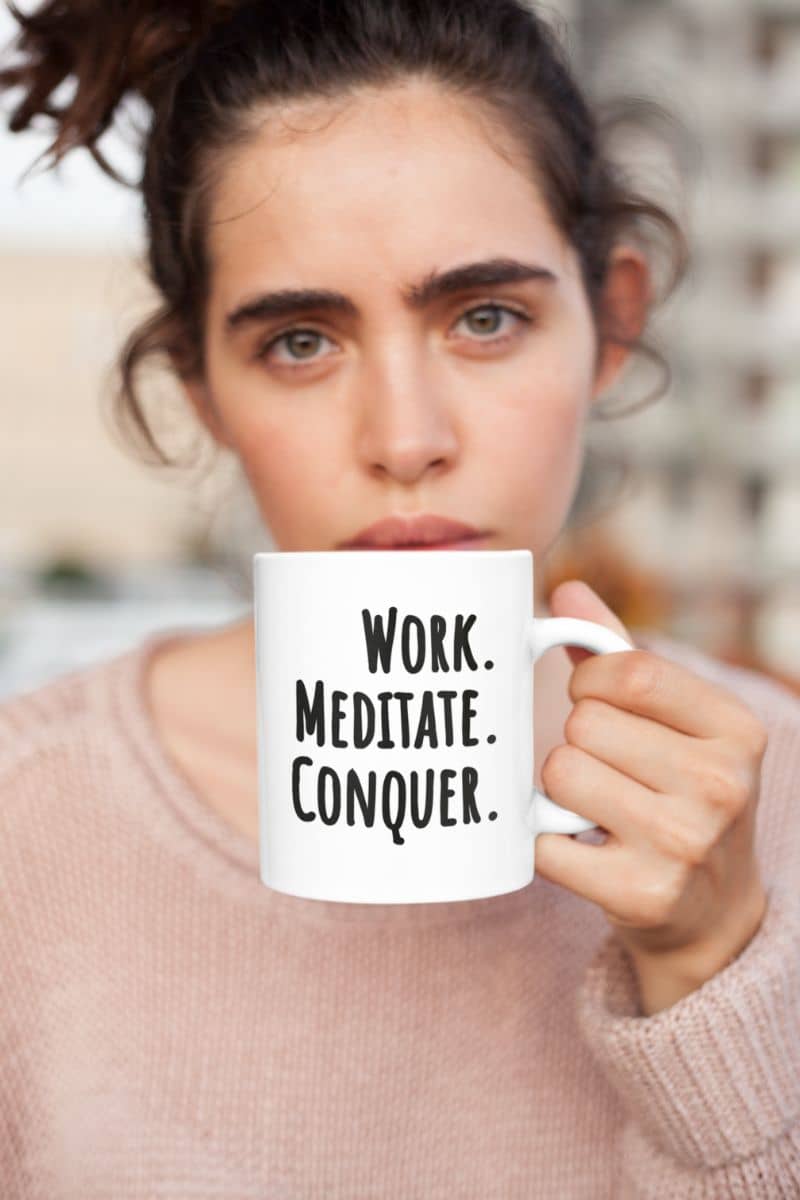 minimalist quote mug with a person holding a mug with 'Work. Meditate. Conquer.' text