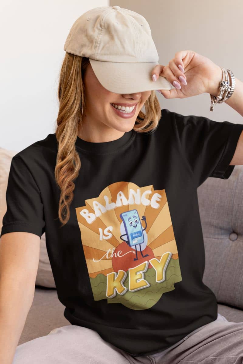 minimalist quote t-shirt with a person wearing a black t-shirt with 'Balance is the Key' text, sitting on a couch.
