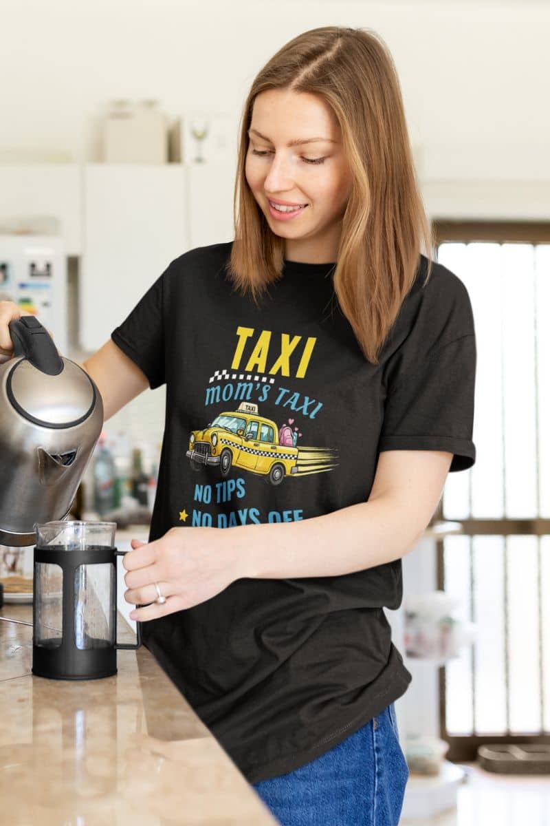 mom life graphic tee with a woman in a kitchen wearing a black t-shirt with a humorous message.