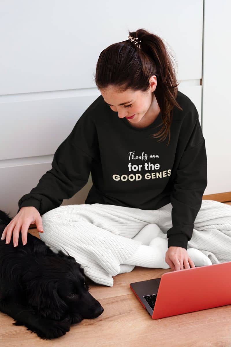mothers day sweatshirt with a woman sitting on the floor with a laptop and a dog, wearing a black sweatshirt with text 'Thanks Mom for the Good Genes'.