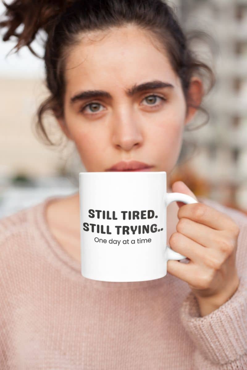 motivation quote mug with a person holding a mug with 'Still Tired. Still Trying. One day at a time' text.