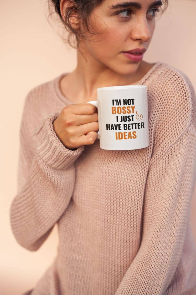 motivational coffee mug with a woman holding a mug with text 'I'm not bossy, I just have better ideas' against a plain background