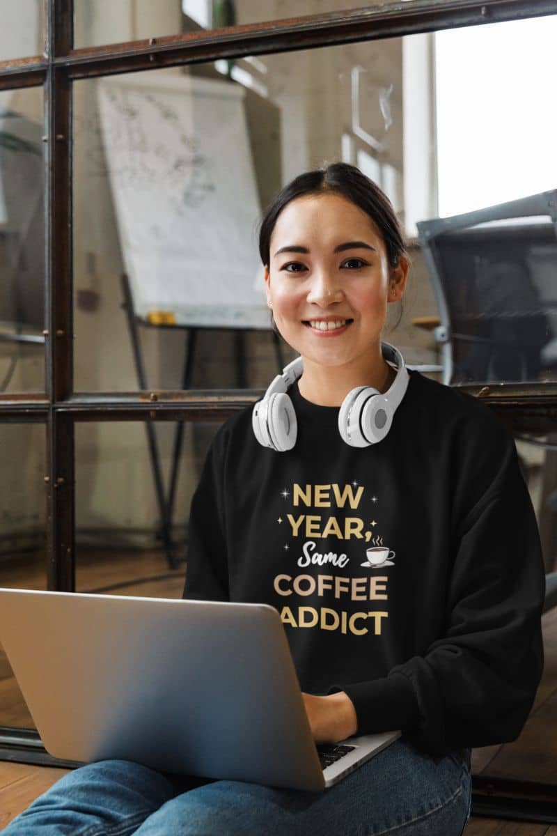 motivational new year sweater with a girl wearing a black sweatshirt with text 'New Year, Same Coffee Addict'