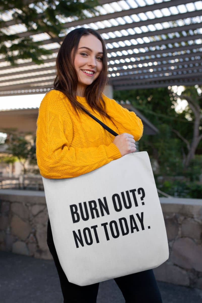 motivational office bag with a woman holding a tote bag with 'BURN OUT? NOT TODAY.' text outdoors.