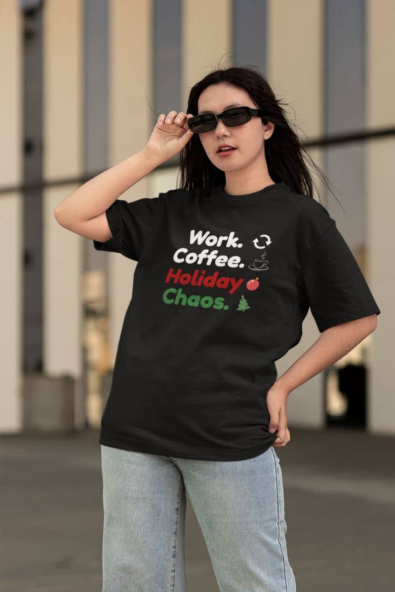 office holiday humor shirt with a person wearing a black t-shirt with text 'Work. Coffee. Holiday Chaos.' and graphics, standing outdoors.