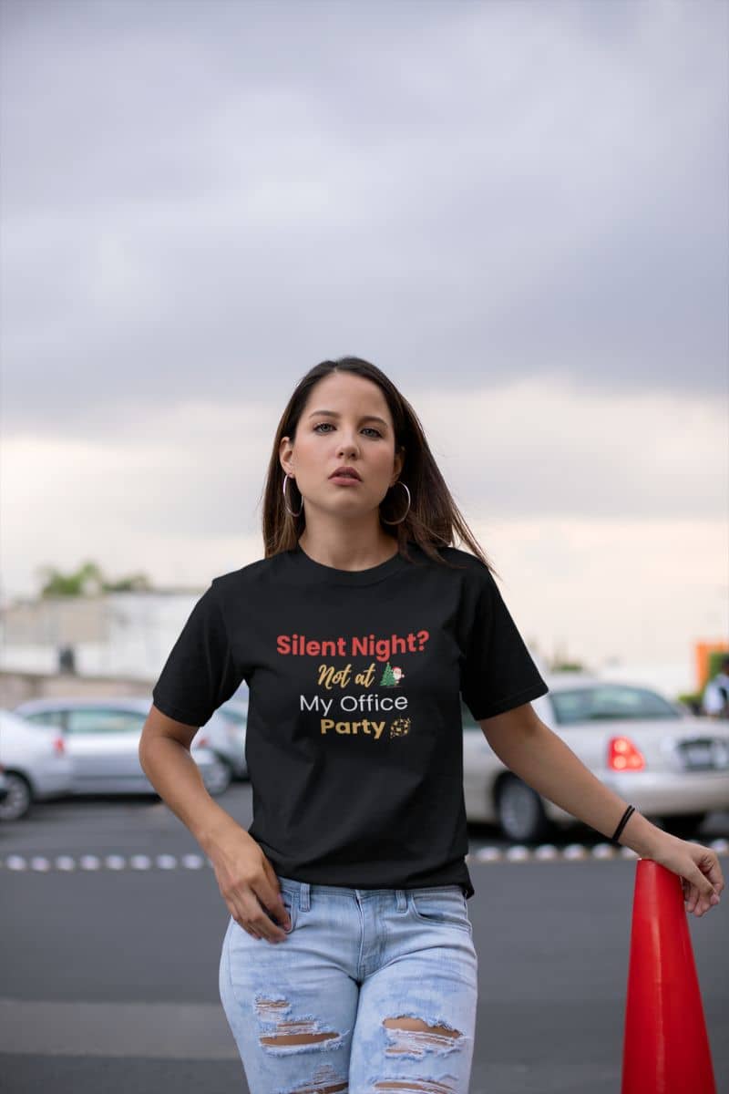 office holiday tee with a woman wearing a black t-shirt with colorful text 'Silent Night? Not at My Office Party' outdoors
