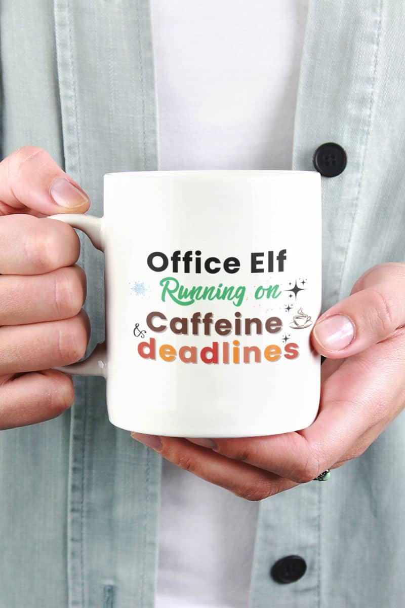 office quote mug with a person holding a mug with 'Office Elf Running on Caffeine and Deadlines' text.