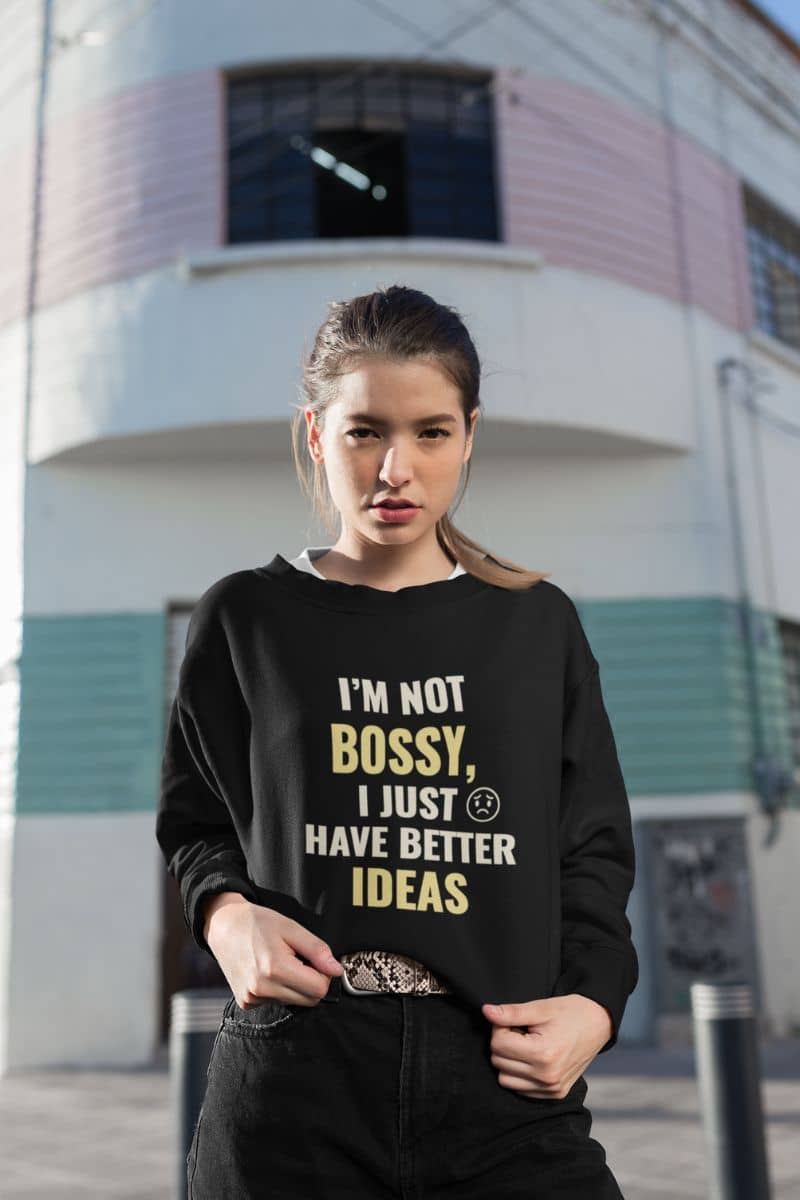 office sarcasm pullover with a woman wearing a black sweatshirt with text 'I’m Not Bossy, I Just Have Better Ideas' in front of a building
