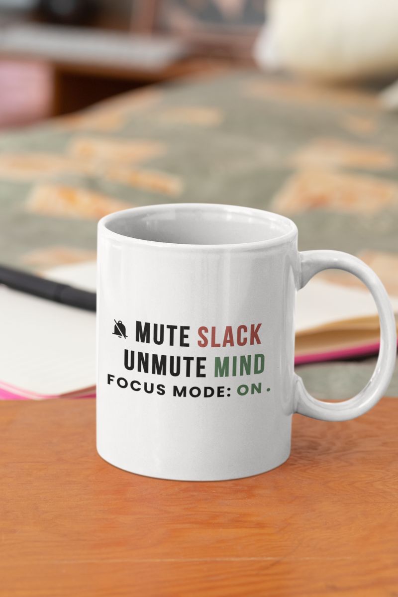 office wellness mug with a white mug featuring the text 'Mute Slack, Unmute Mind. Focus Mode: On' on a wooden surface