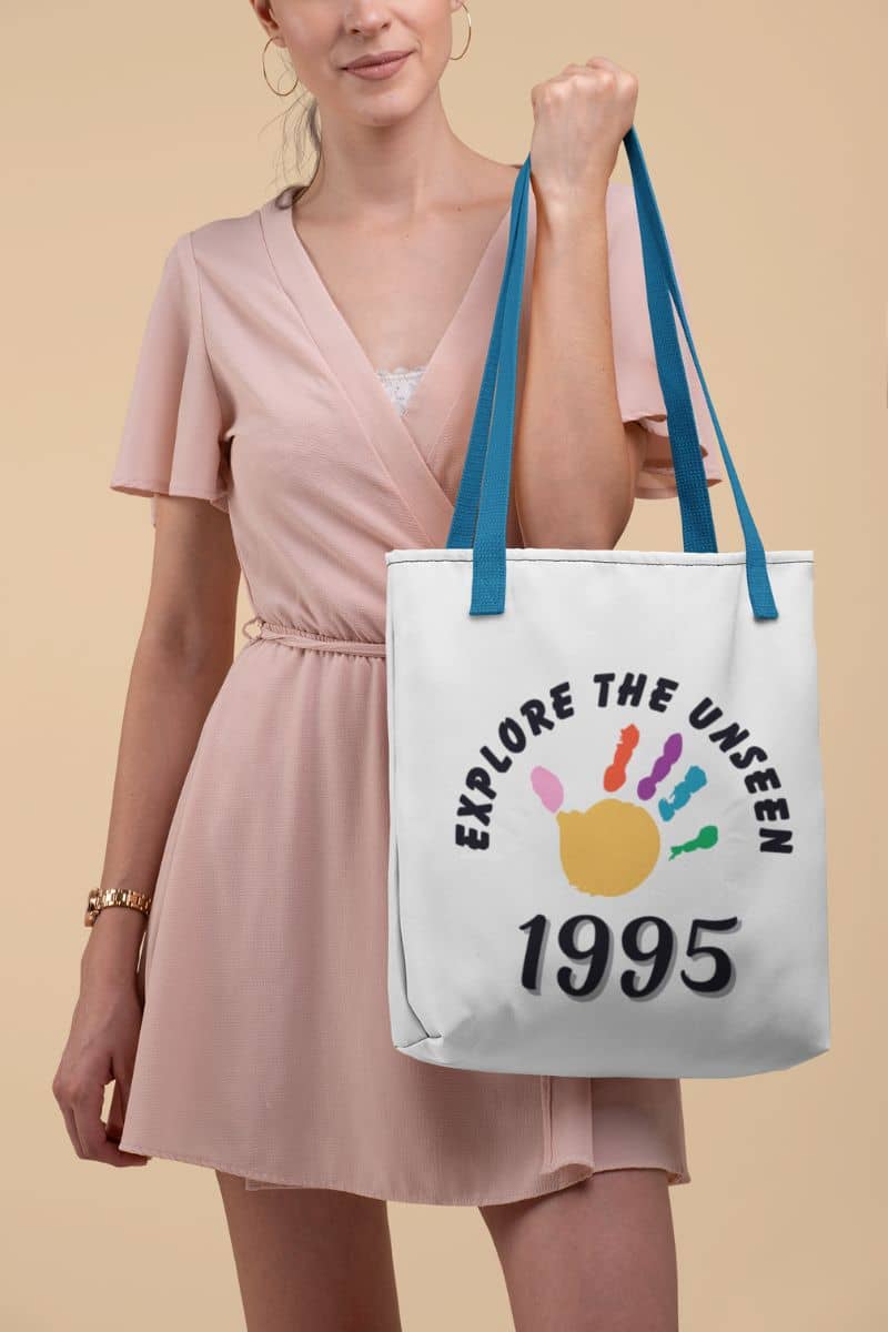 outdoor lifestyle bag with a woman holding a tote bag with 'Explore the Unseen 1995' design on a beige background