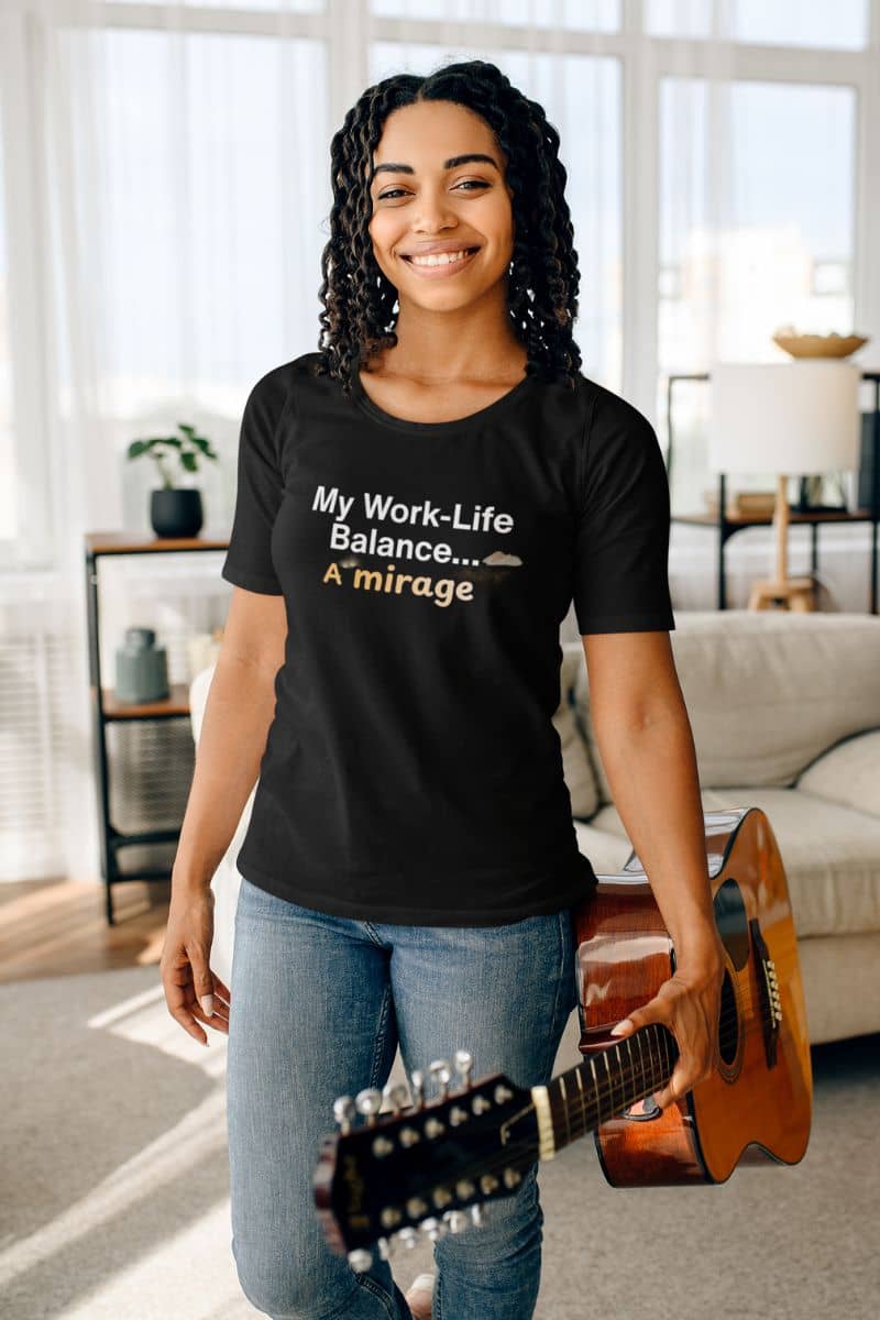 Overworked introvert shirt with a woman wearing a black t-shirt with text, holding a guitar in a living room.