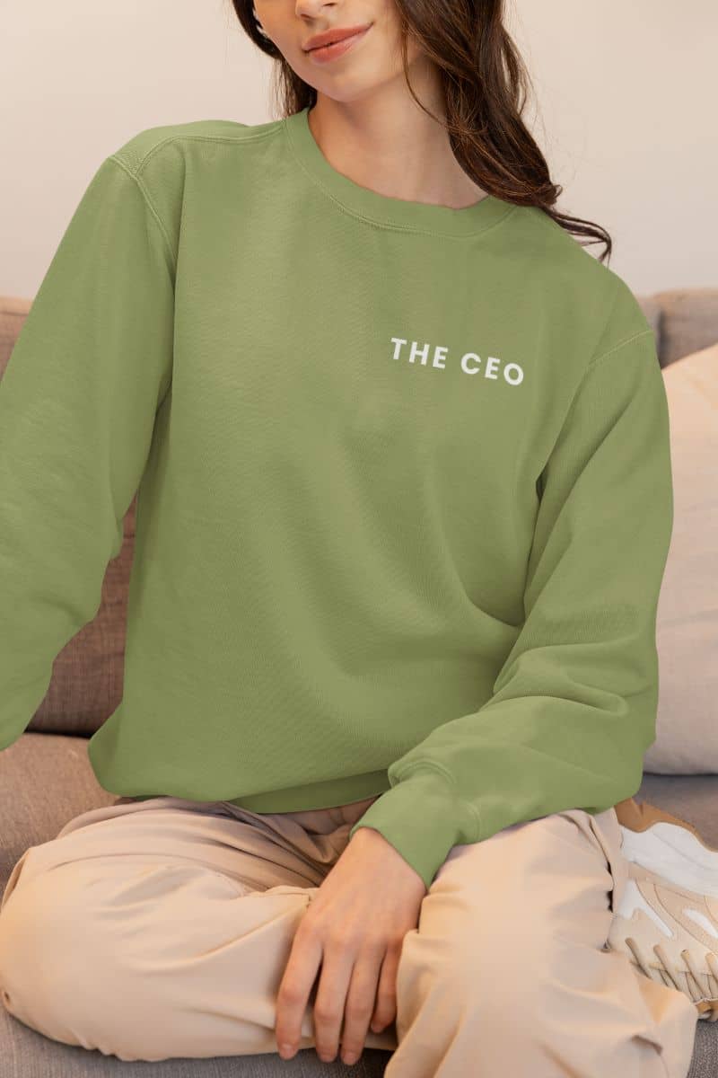 personalized couple sweatshirts with a person wearing a green sweatshirt with 'THE CEO' text, sitting on a couch.