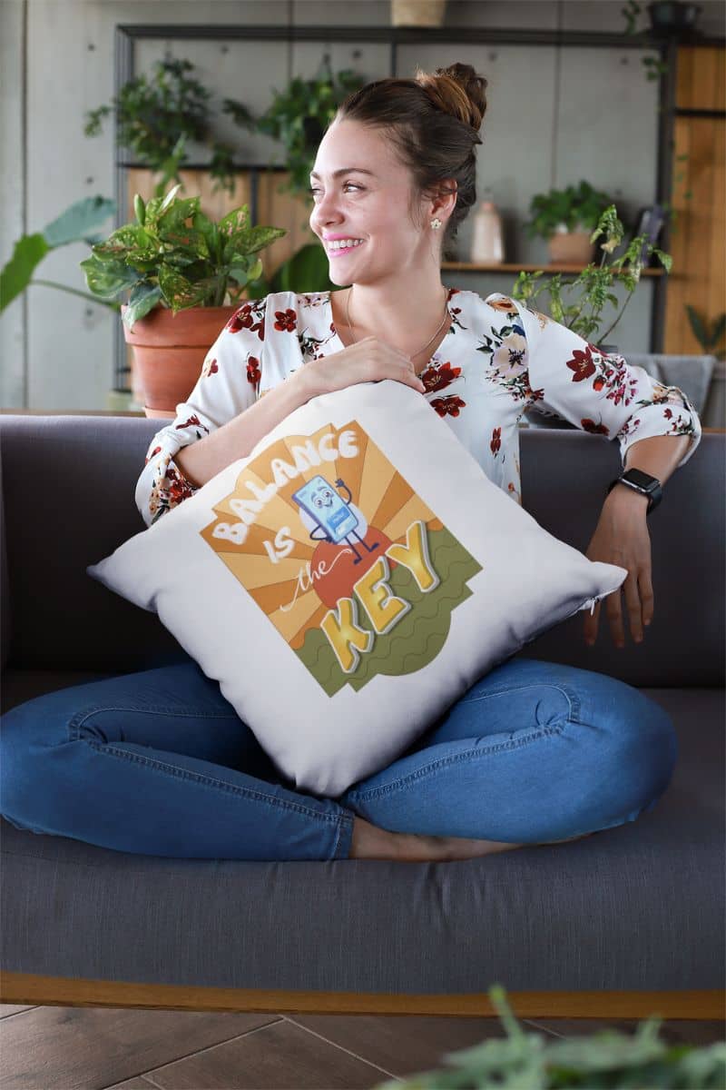 positive affirmation pillow with a woman holding a pillow with 'Balance is the Key' text in a home setting
