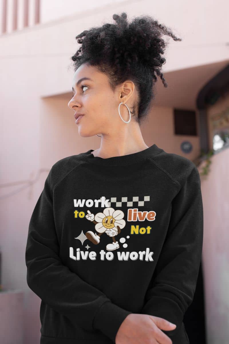 positive message sweater with a person wearing a black sweatshirt with the quote 'Work to Live, Not Live to Work' and flower design.