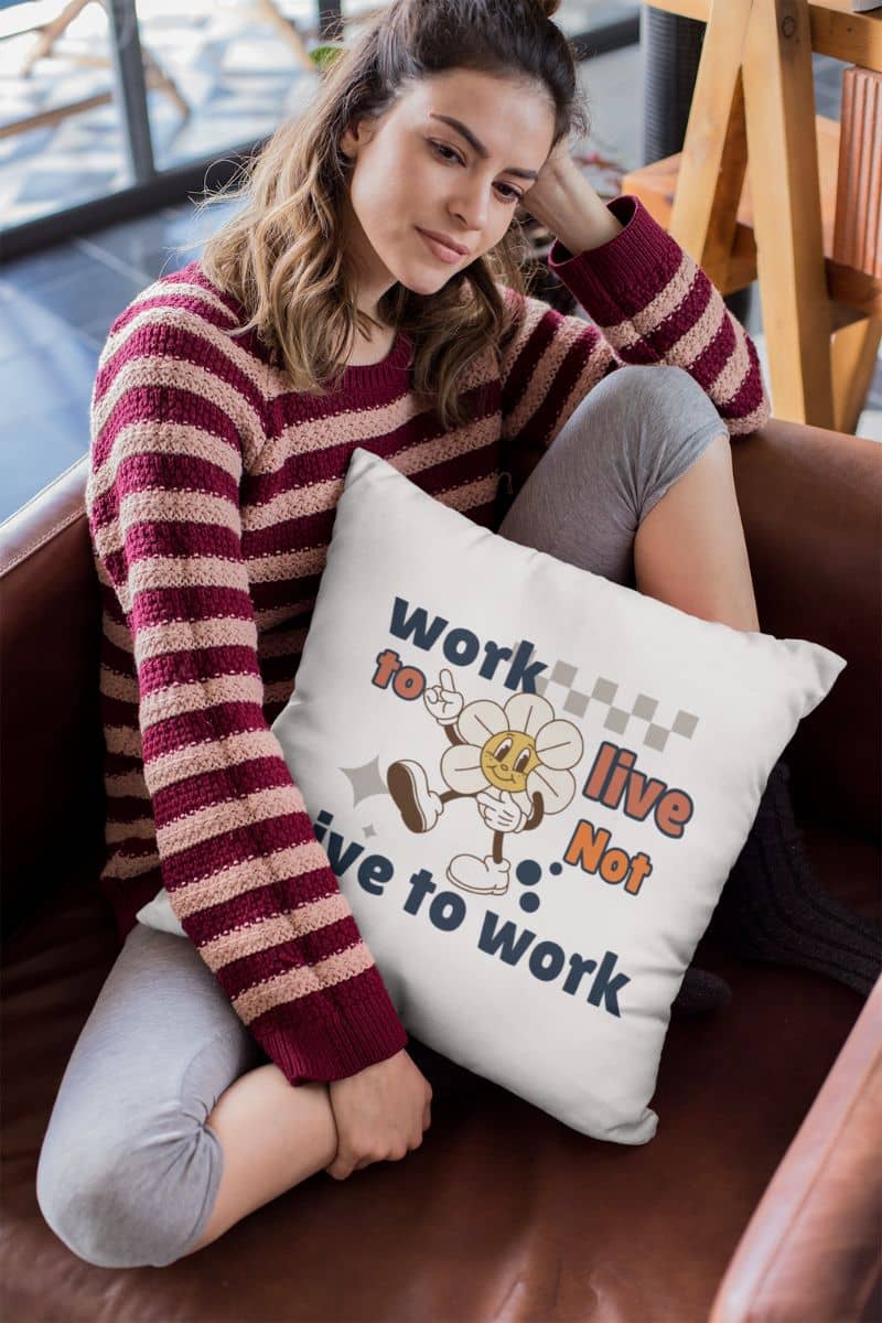 positive vibe pillow with a woman sitting on a couch with a pillow featuring text 'Work to Live, Not Live to Work' and graphics.