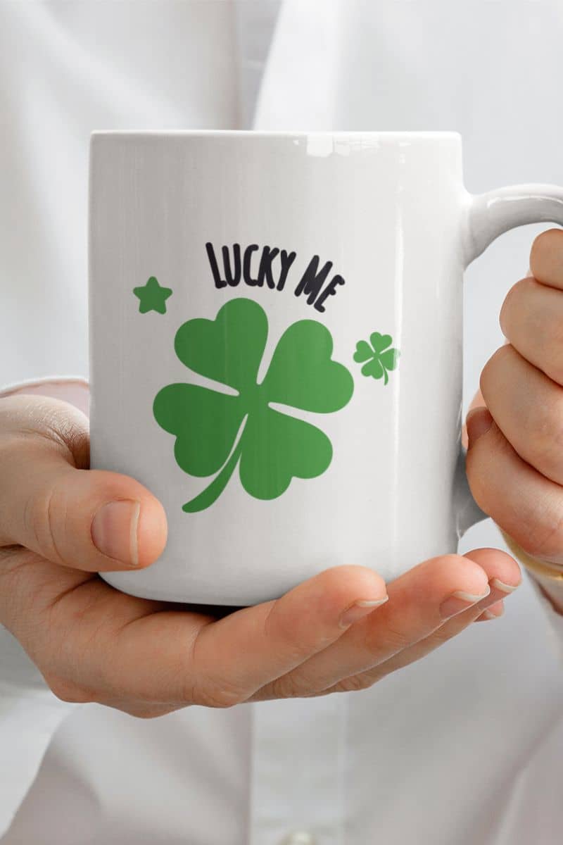 positive vibes mug with a white mug with green four-leaf clover and 'Lucky Me' text held by a person.
