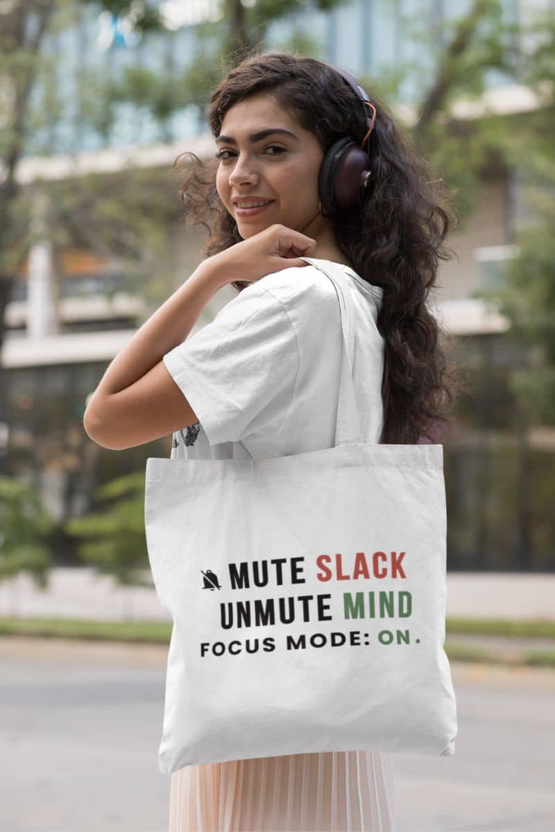 productivity tote bag with a woman holding a tote bag with text 'Mute Slack, Unmute Mind. Focus Mode: On' in an urban setting