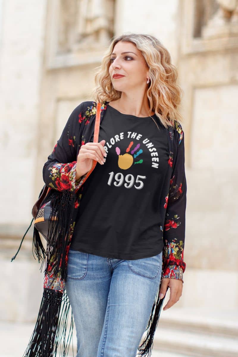 quote graphic t-shirt with a woman wearing a black graphic t-shirt with 'Explore the Unseen' text, standing outdoors.