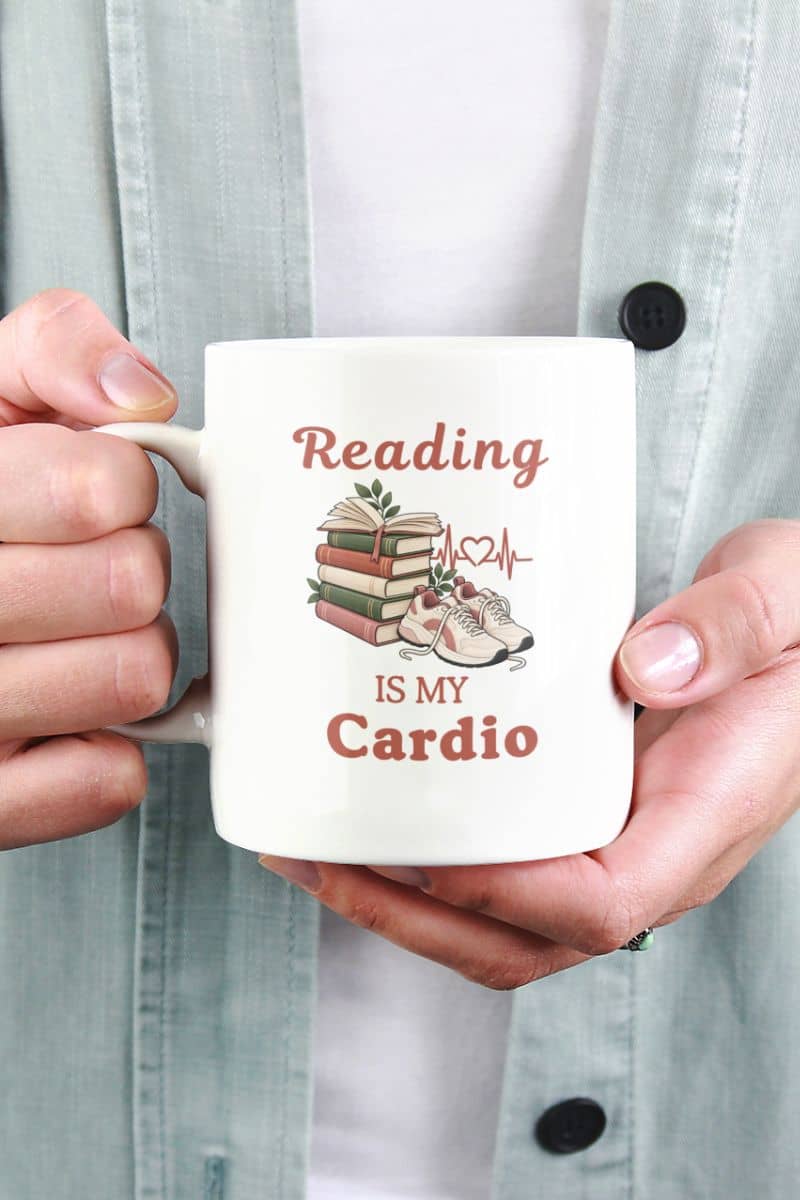 reading mug with a person holding a white ceramic mug featuring the text 'Reading IS MY Cardio' 