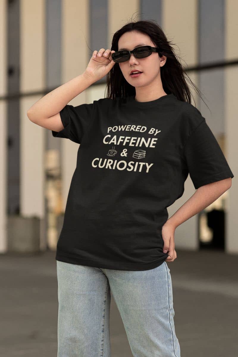 reading shirt with a woman wearing a black t-shirt with text 'Powered by Caffeine & Curiosity'.