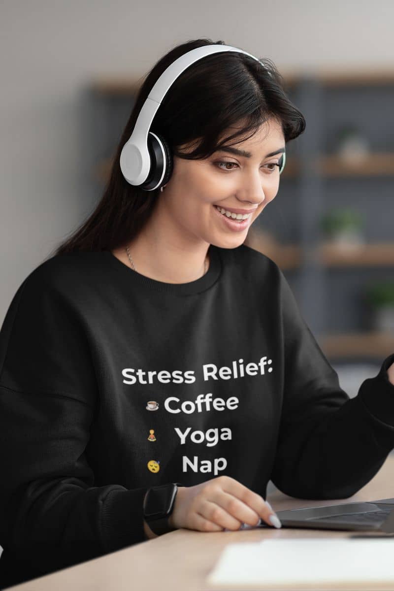 remote work burnout hoodie with a woman wearing headphones and a black sweatshirt with text, sitting at a desk.