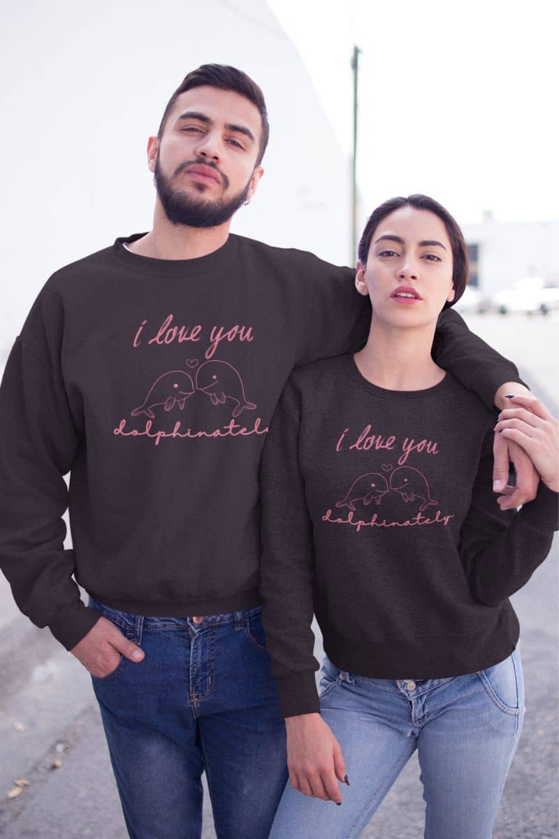 romantic animal sweatshirt with two people wearing matching black sweatshirts with 'I love you dolphinately' text.