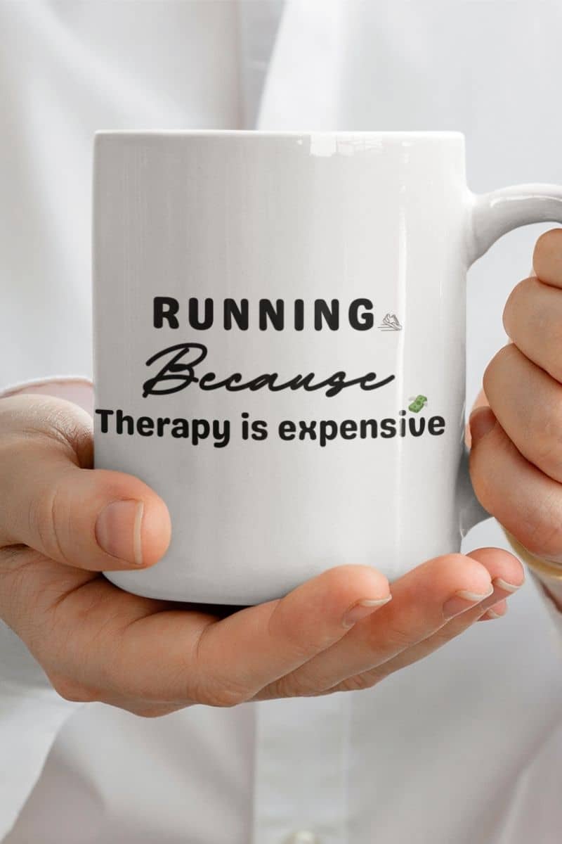 runner coffee mug with a person holding a mug featuring the text 'Running because therapy is expensive'