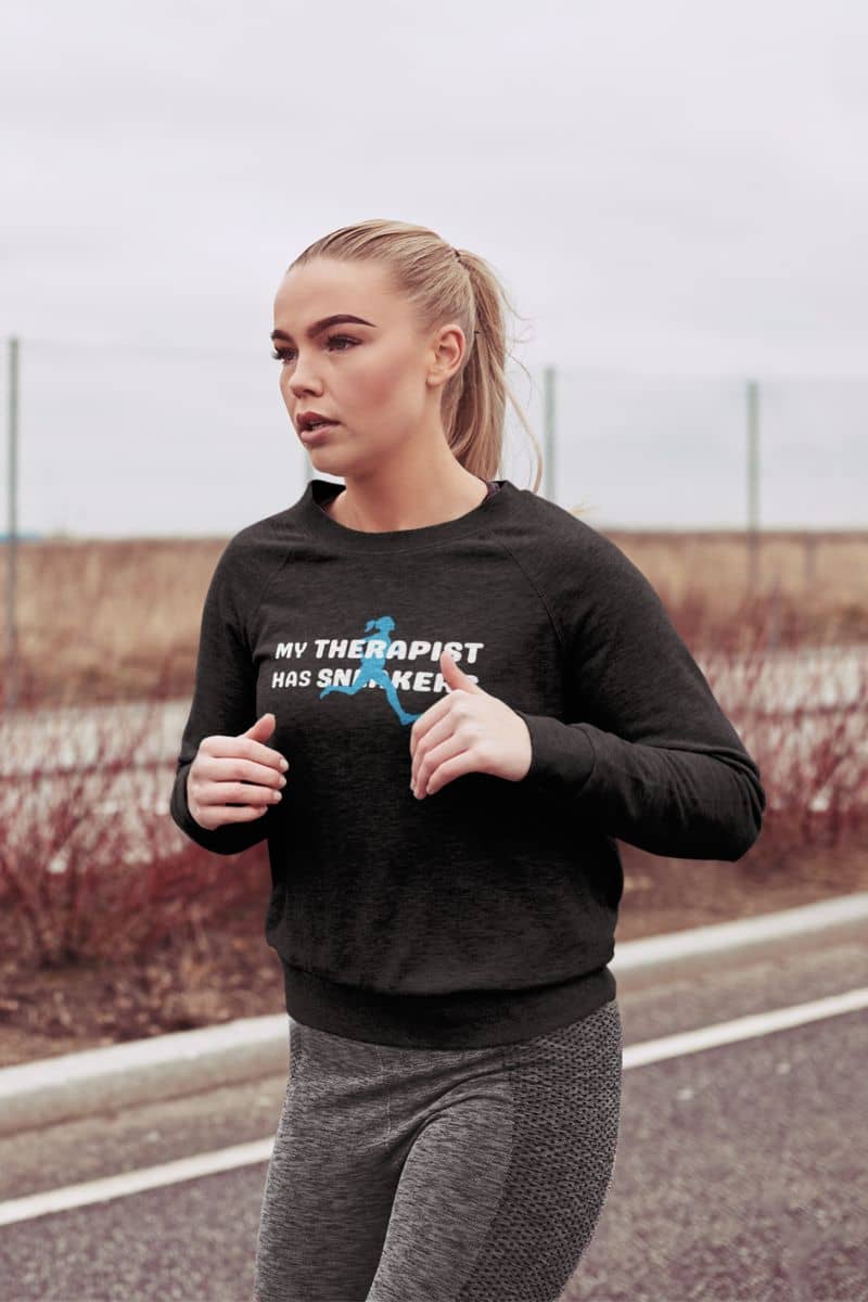 runner gift sweatshirt with a woman wearing a black sweatshirt with text 'My Therapist Has Sneakers', standing outdoors.