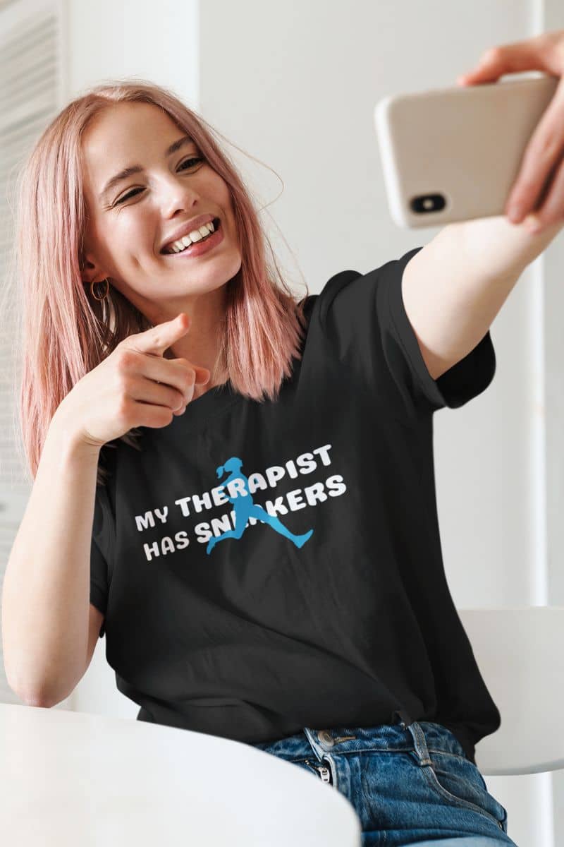 runner humor t-shirt with a person wearing a black t-shirt with text 'My Therapist Has Sneakers' and taking a selfie.