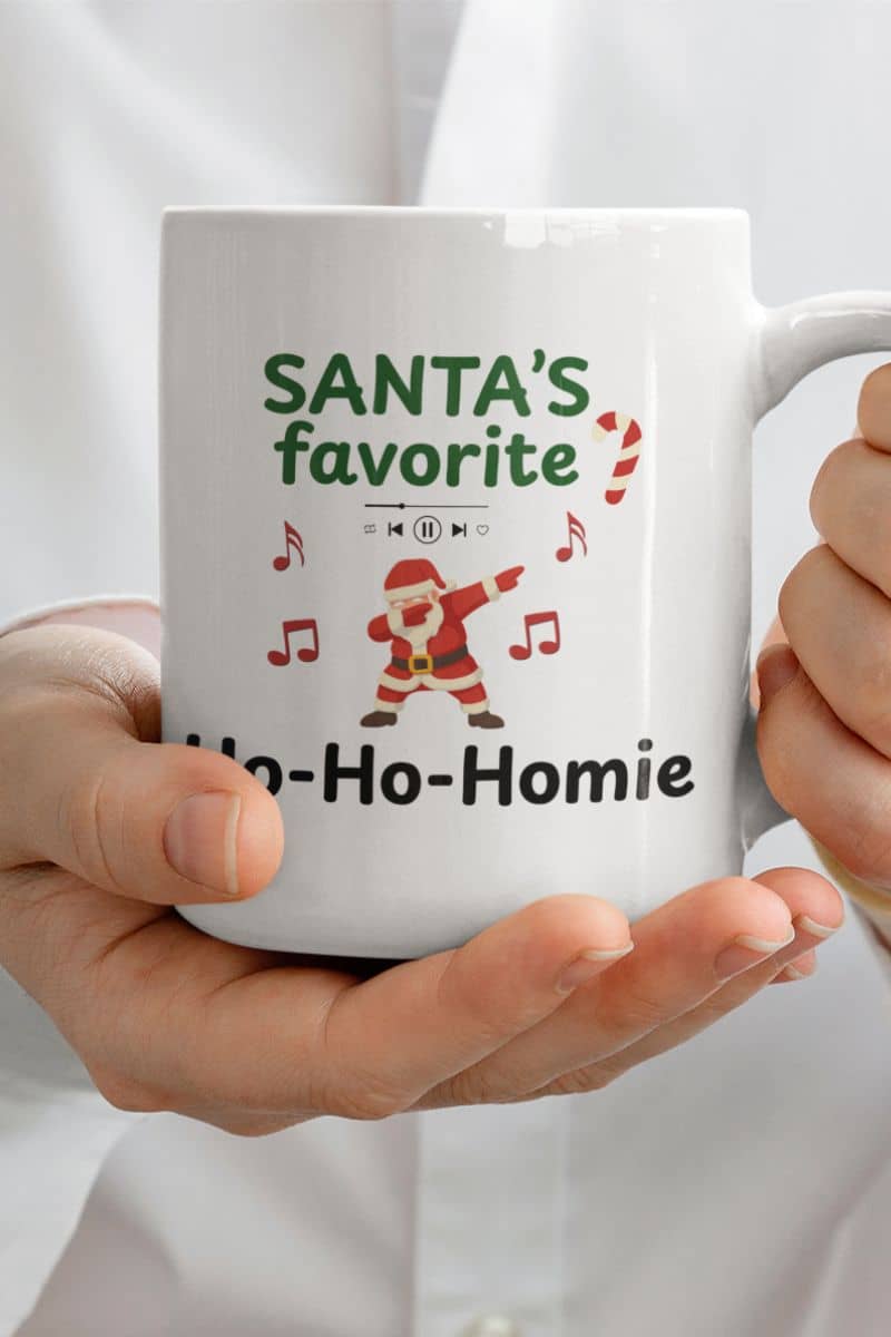 santa holiday mug with a mug with 'Santa's favorite Ho-Ho-Homie' text held by a person