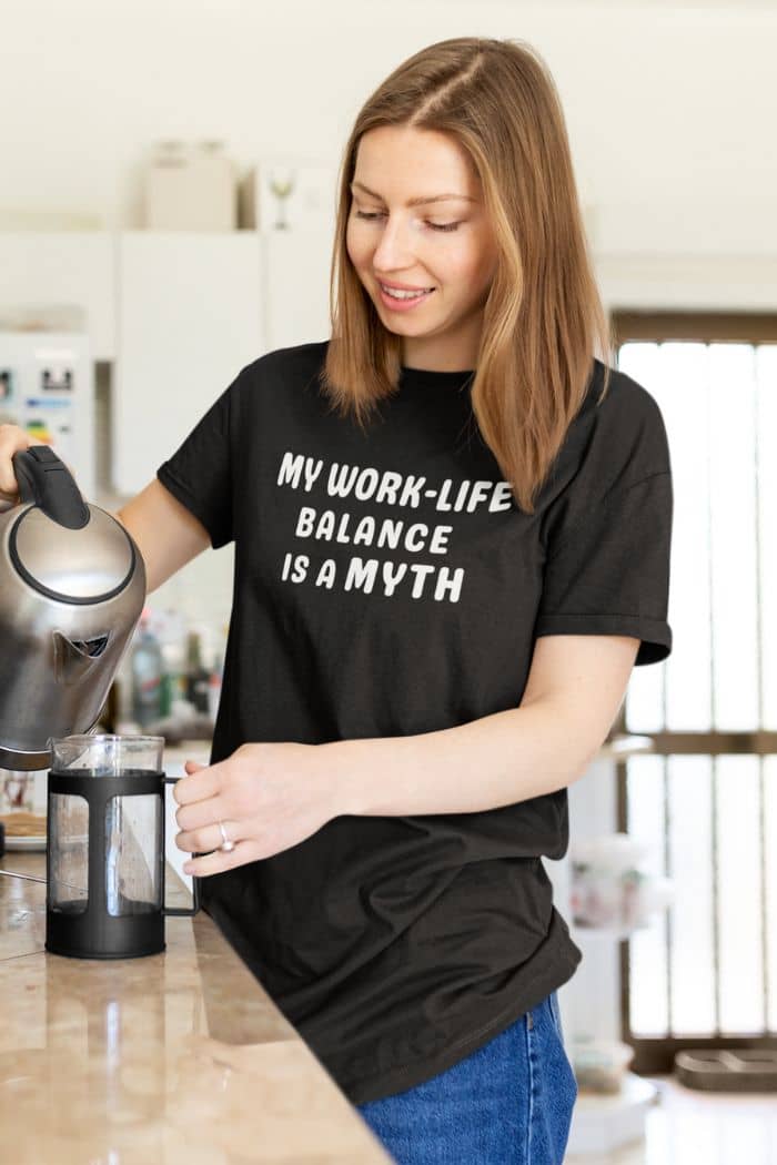 sarcastic office shirt with a woman in a kitchen wearing a black t-shirt with 'MY WORK-LIFE BALANCE IS A MYTH' text.