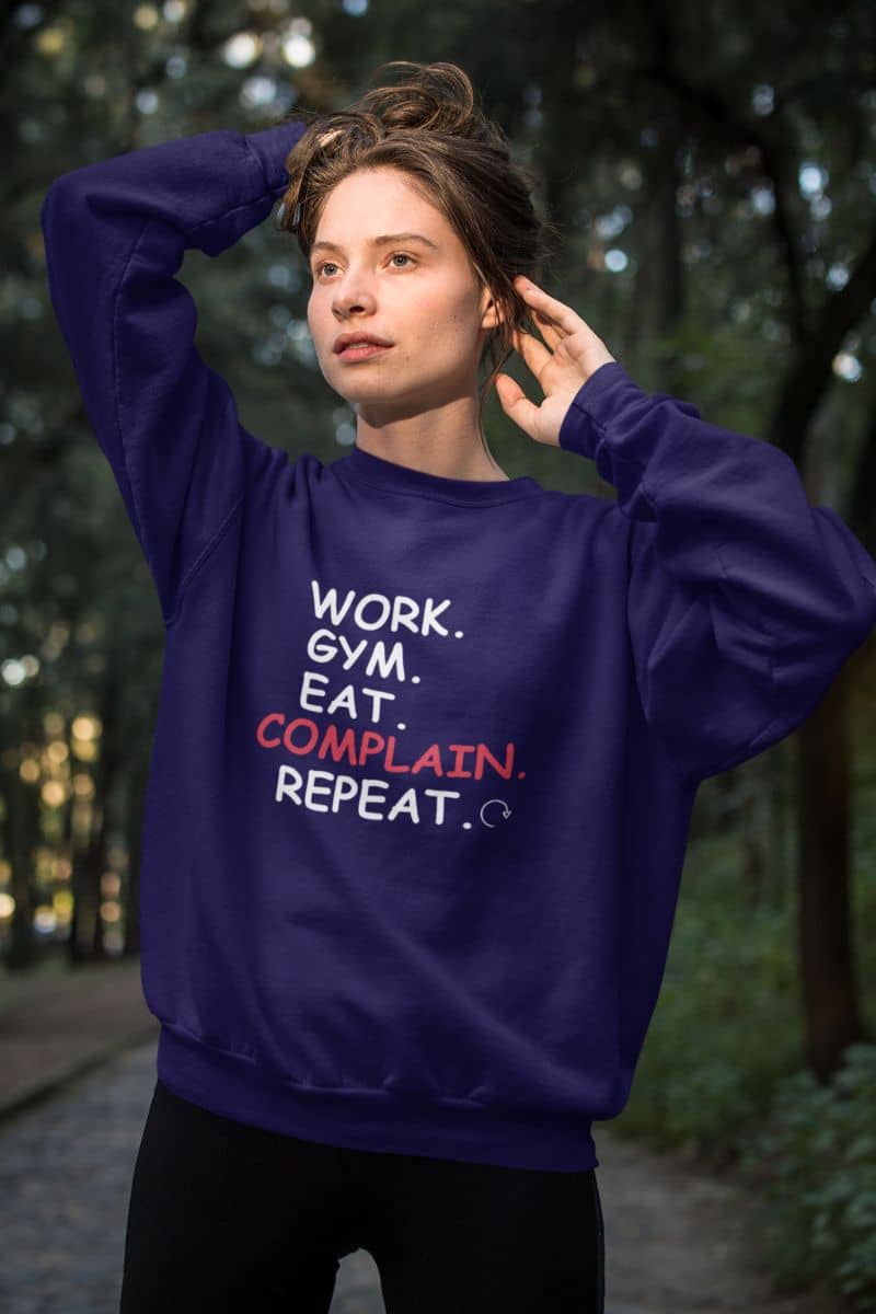 sarcastic quote pullover with a person wearing a purple sweatshirt with text 'Work. Gym. Eat. Complain. Repeat' in a forest setting