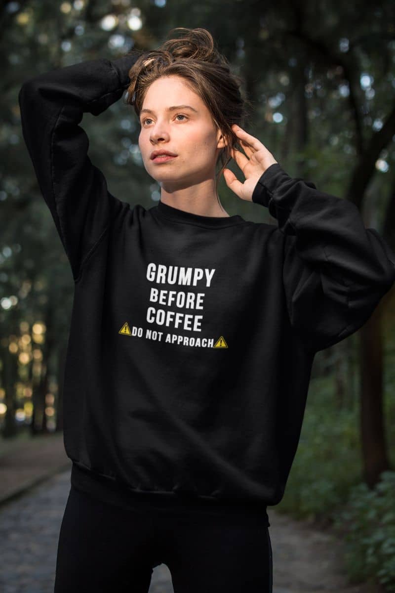 sarcastic quote sweatshirt with a person wearing a black sweatshirt with text 'Grumpy before coffee, do not approach' in a forest setting