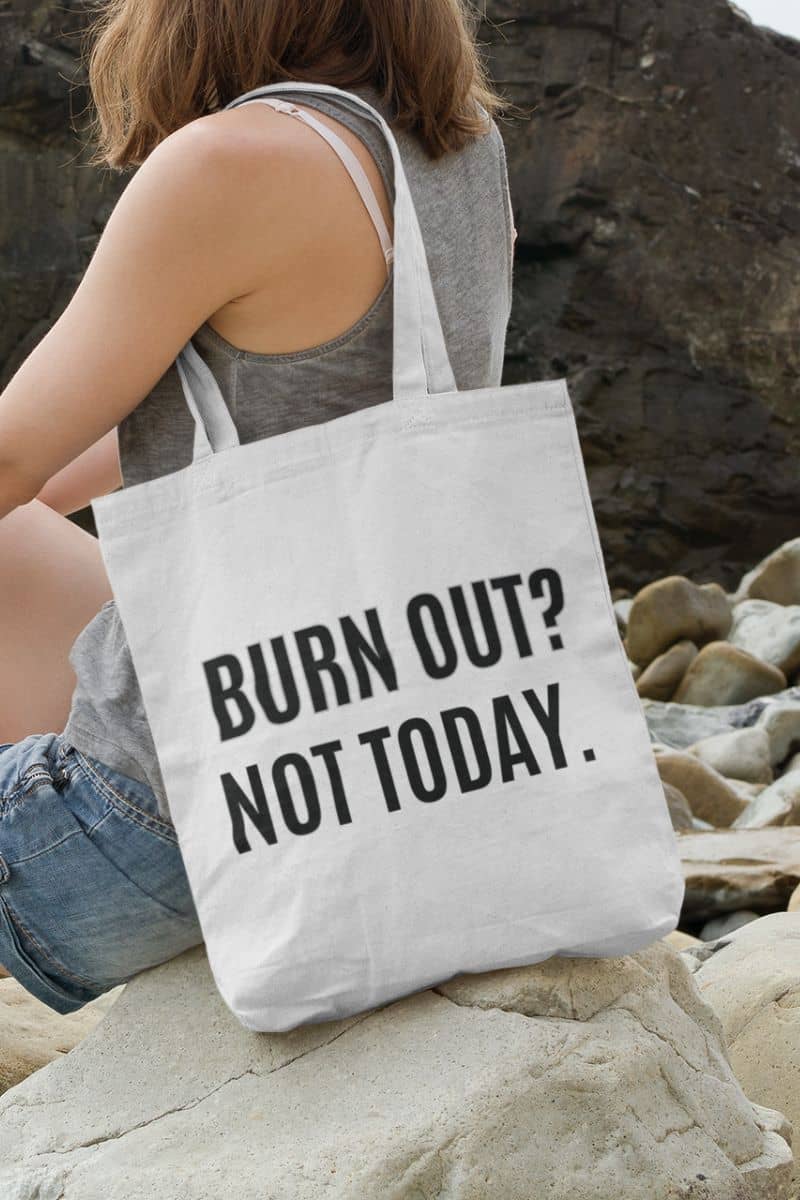 sarcastic work tote with a person holding a tote bag with 'BURN OUT? NOT TODAY.' text on a rocky surface.