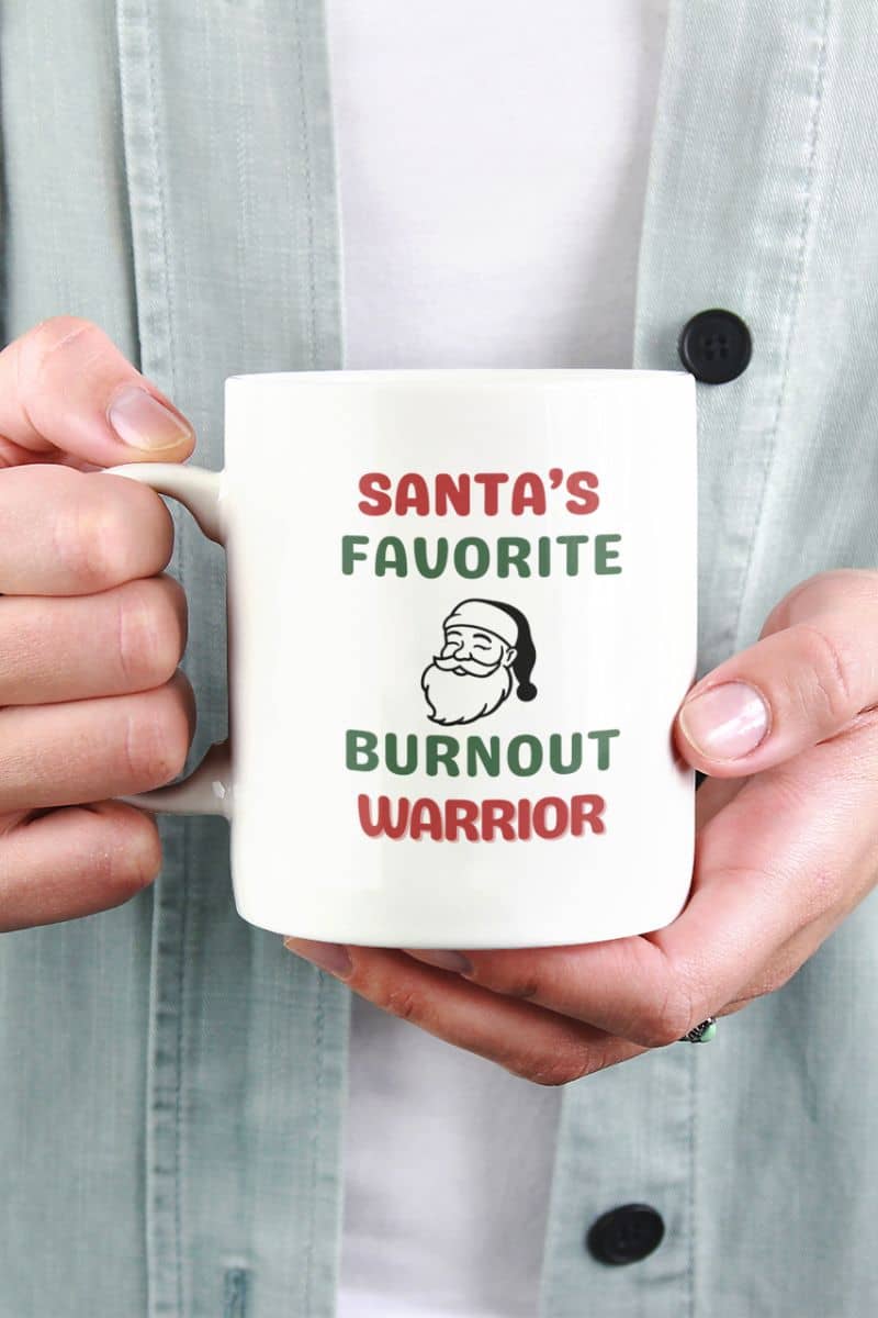 secret santa coffee mug with a person holding a mug with 'Santa's Favorite Burnout Warrior' text and graphic.