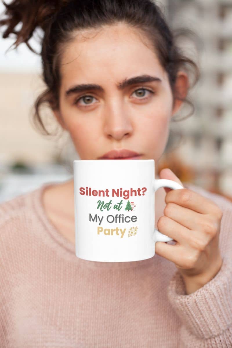 secret santa mug with a person holding a mug with text 'Silent Night? Not at My Office Party' against a blurred background