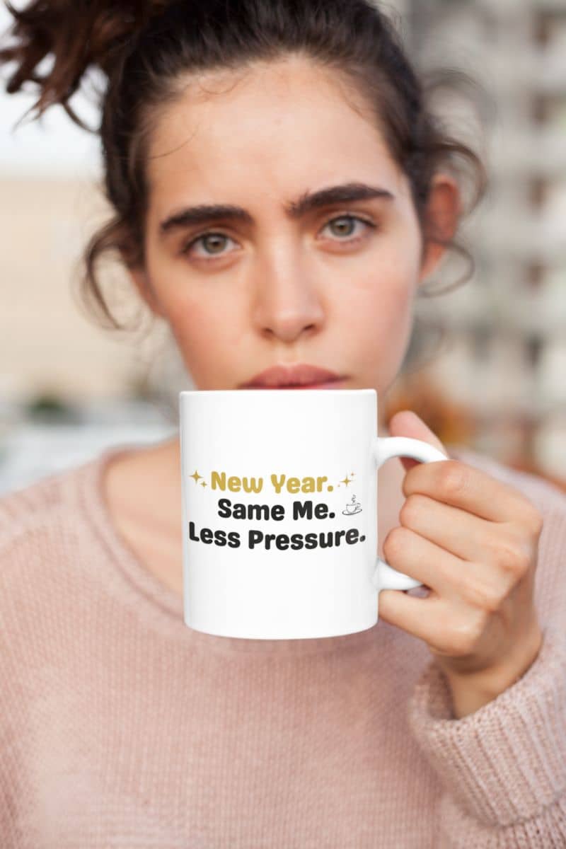 self care mug with a person holding a mug with text 'New Year, Same Me, Less Pressure' against a blurred background